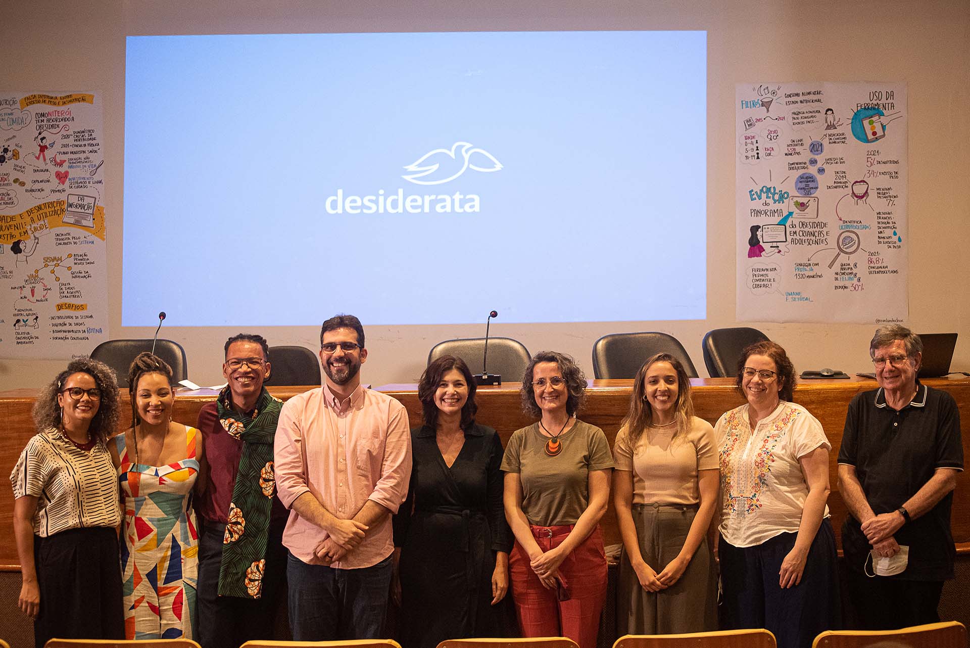 Grupo de pessoas posando para a foto à frente de uma tela com a marca do Isntituto Desiderata